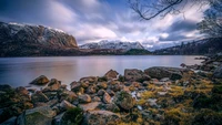 Lago de alta montanha sereno com reflexos de montanhas e costa rochosa