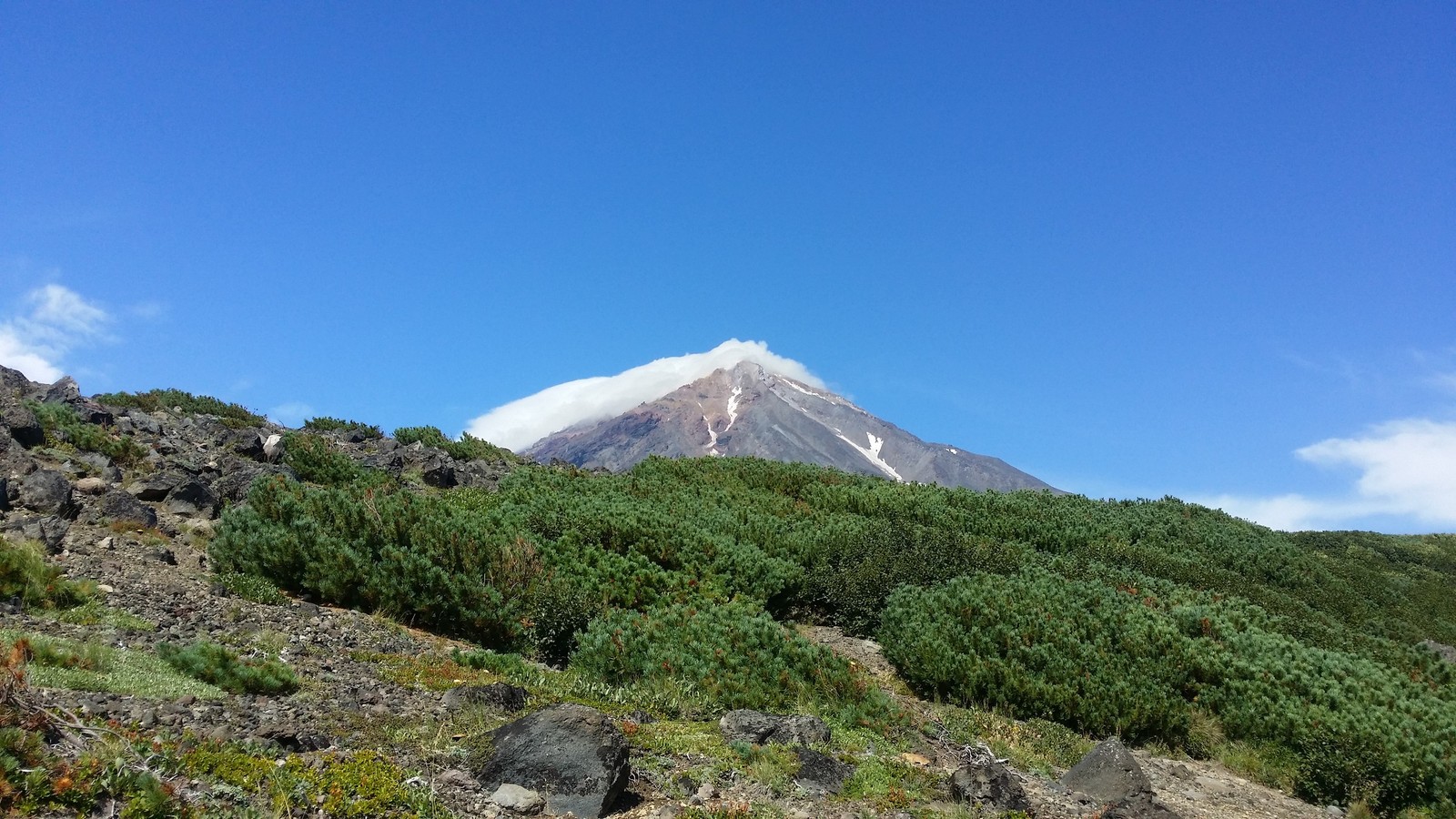 A view of a mountain with a snow capped peak in the distance (mount scenery, volcano, highland, mountainous landforms, mountain)