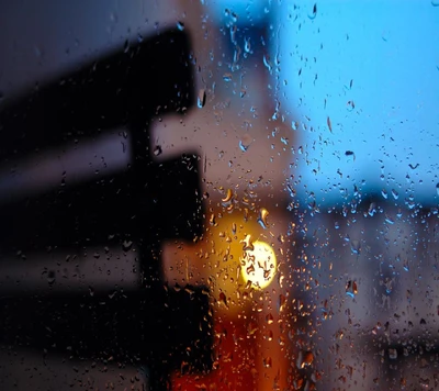 Gotas de lluvia en una ventana con un brillo cálido en el fondo.