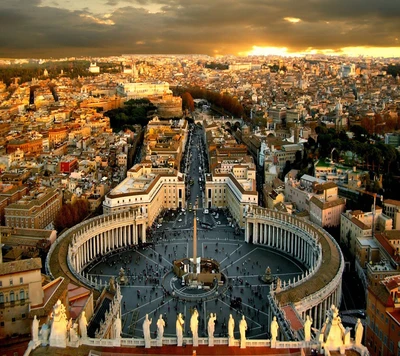 Vue aérienne de la Cité du Vatican au coucher du soleil, mettant en valeur la basilique Saint-Pierre et le paysage urbain environnant.