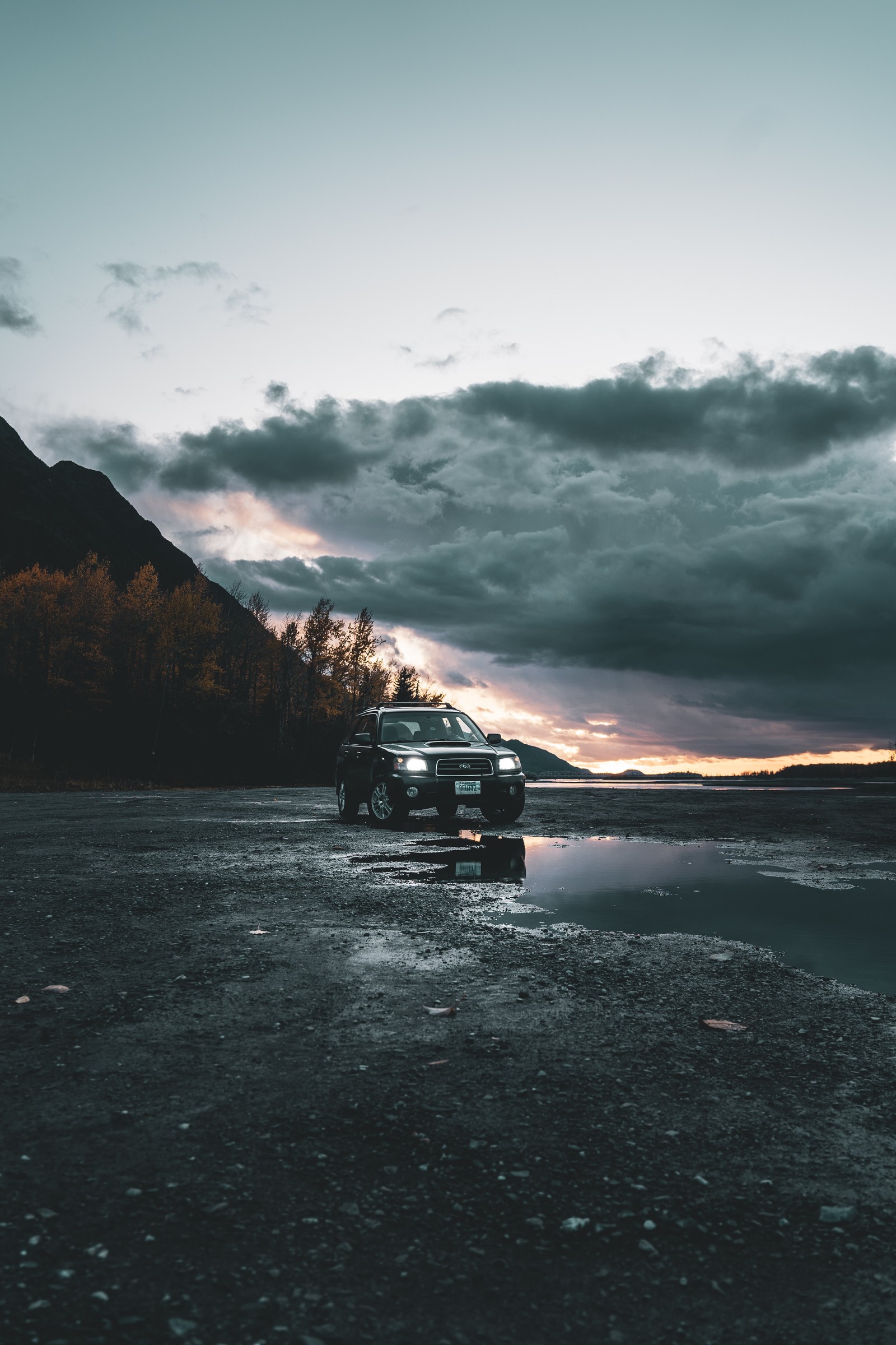 Un camion arafed garé sur une plage sous un ciel nuageux (son, horizon, océan, loch, eau)