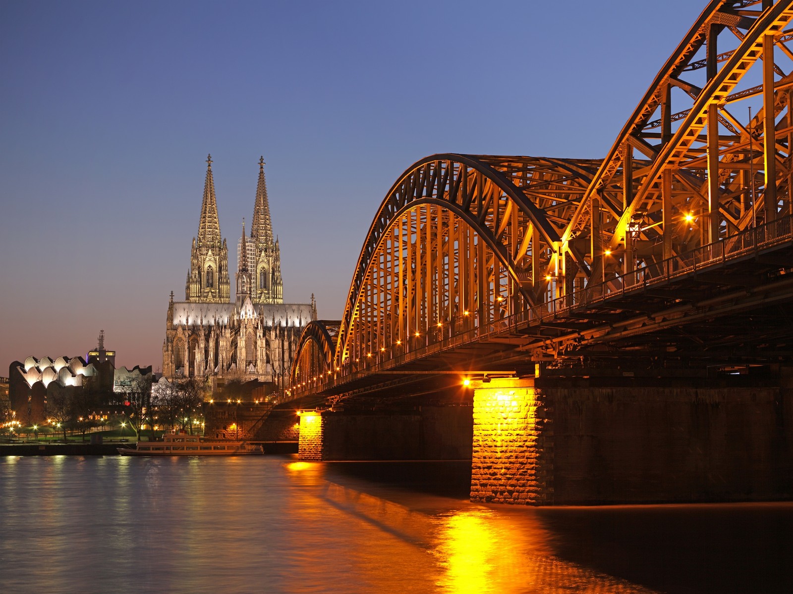 Verschwommene brücke über das wasser mit einer kathedrale im hintergrund. (abend, architektur, brücke, kölner, sehenswürdigkeit)