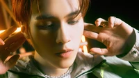 Hendery do NCT, capturado em um momento de introspecção com um fundo vibrante e iluminado.