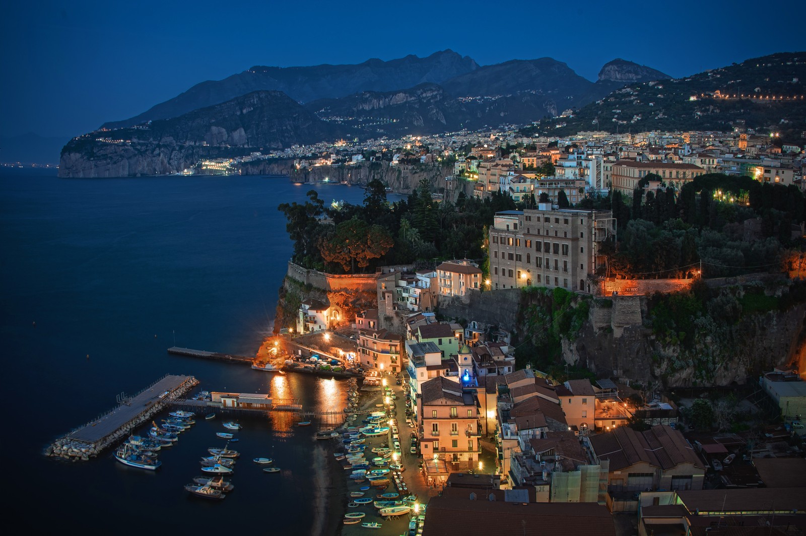 Vista aérea de uma cidade à noite com barcos atracados no porto (sorrento, cidade, paisagem urbana, noite, área urbana)