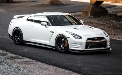 Elegante Nissan GT-R blanca con llantas personalizadas en una carretera urbana.