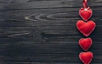 Corazones rojos hechos a mano colgando de un fondo de madera para el Día de San Valentín