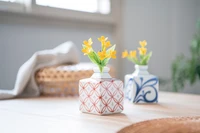 Ceramic vases with yellow flowers on a wooden table, enhancing interior design.