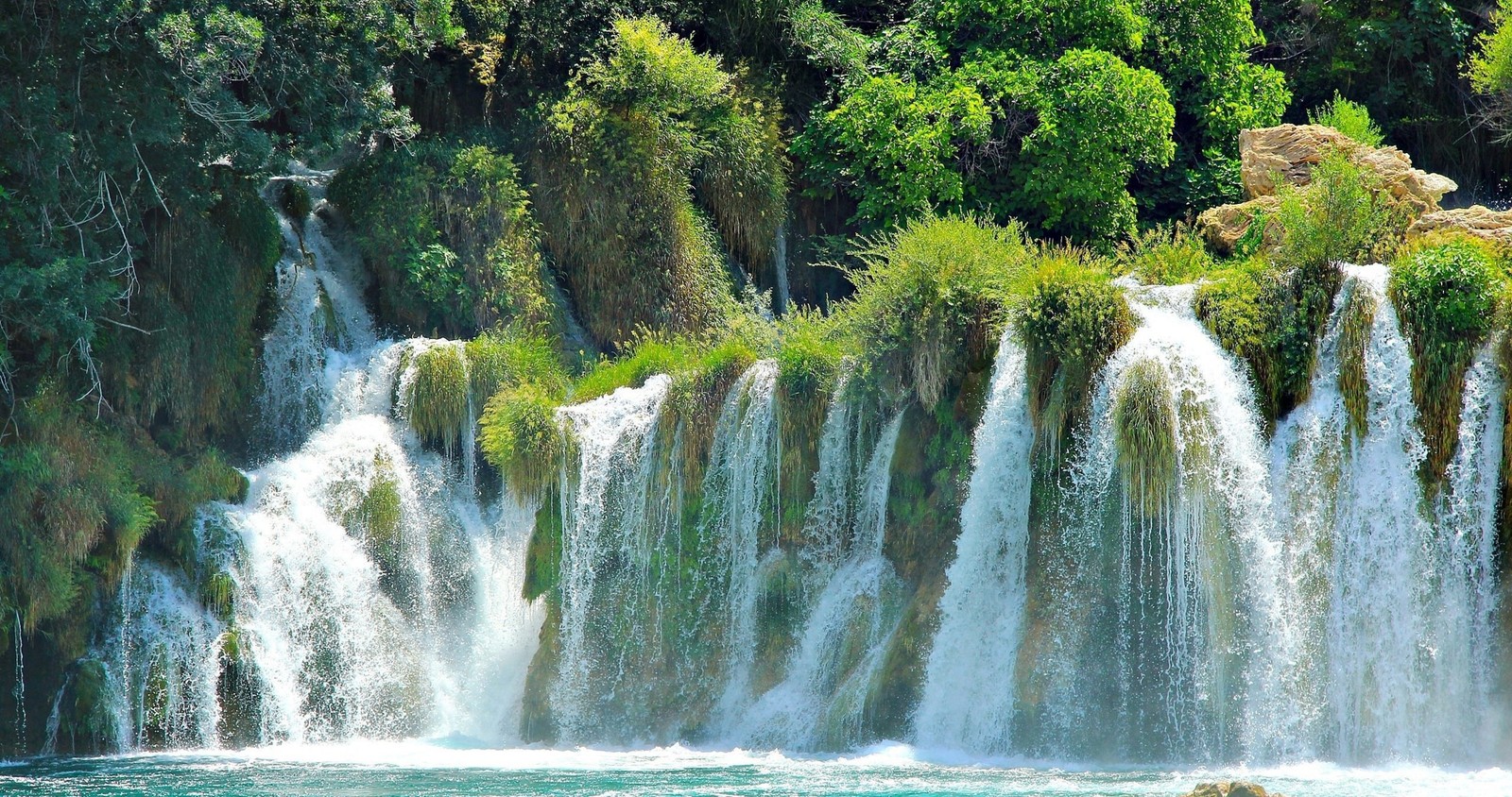 A close up of a waterfall with a person standing on a rock (krka national park, waterfall, national park, park, nature)