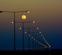 Luna llena iluminando una calle bordeada de farolas