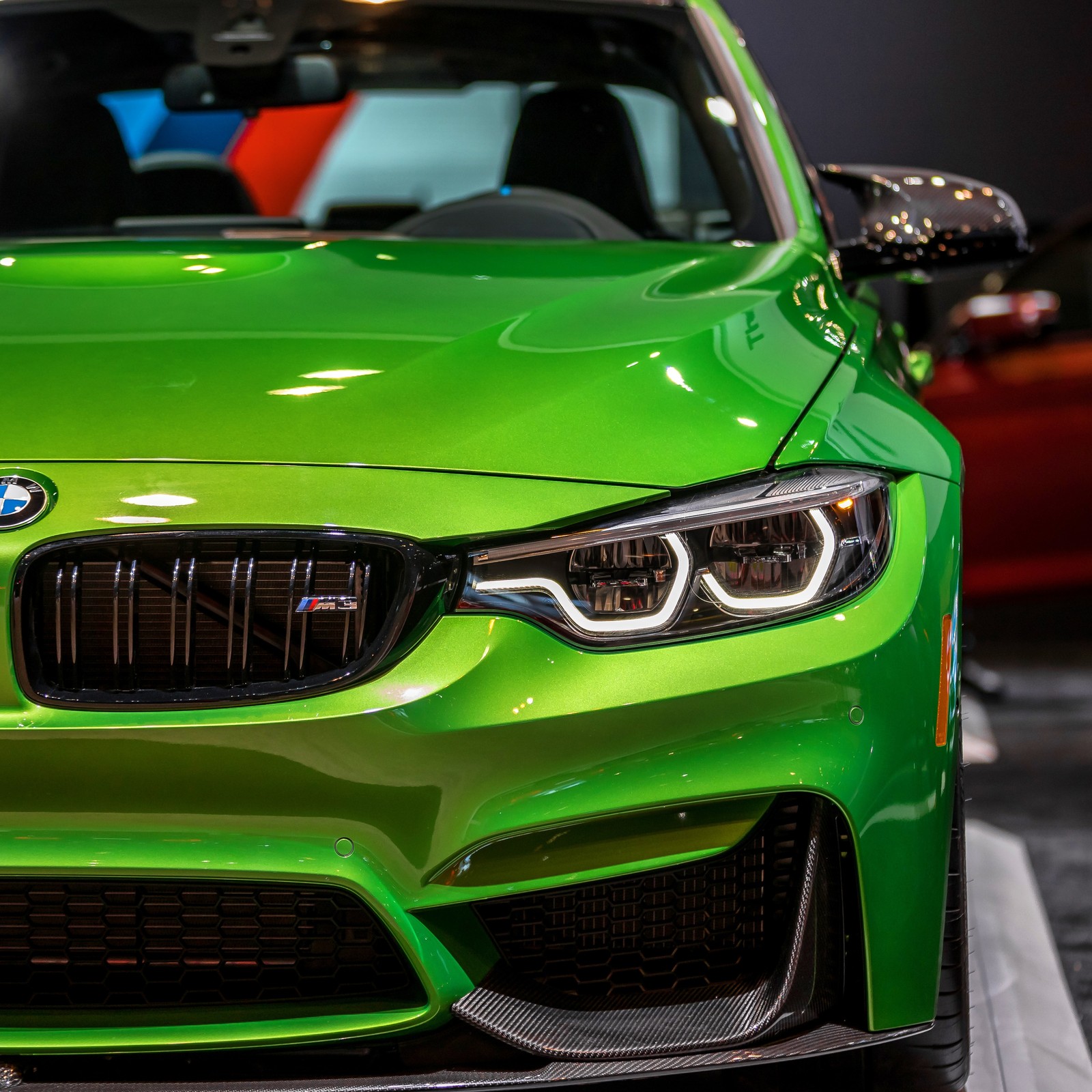 A close up of a green car parked in a showroom (car, m3 bmw)