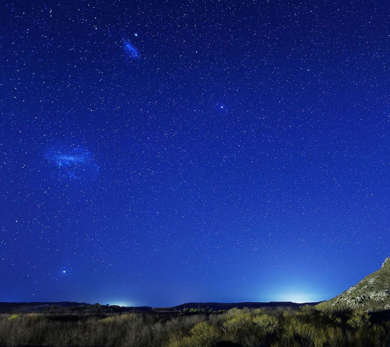 Una vista de una montaña con un cielo lleno de estrellas (horizonte, naturaleza, noche)