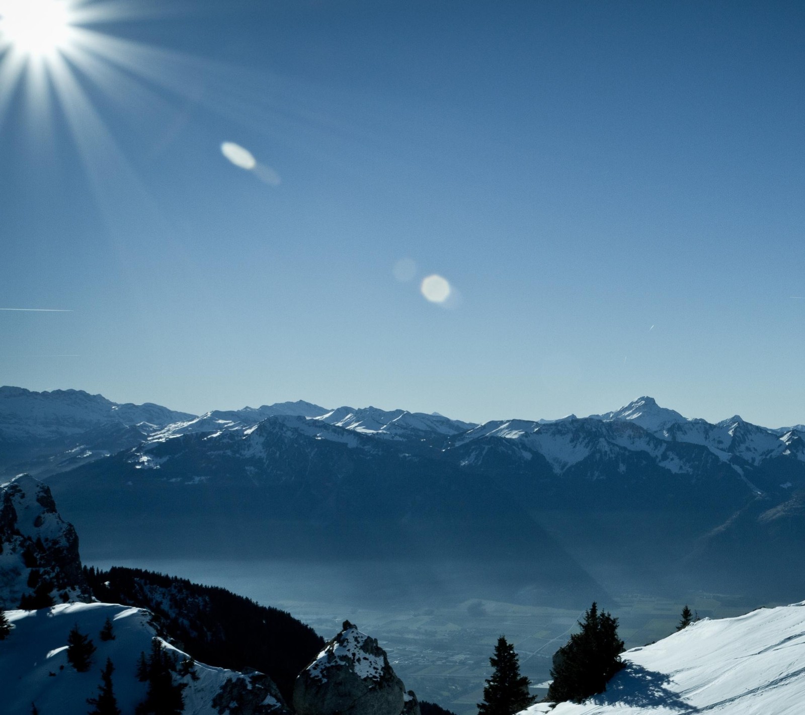 Skiers on a mountain slope with a view of a lake and mountains (beautiful, nature, sky, sun)