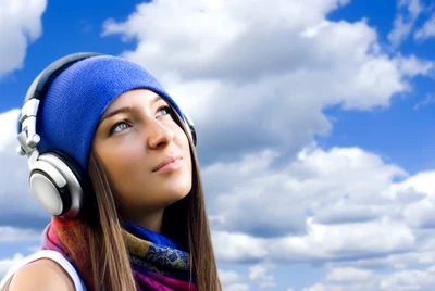 Fille avec des écouteurs contre un ciel bleu