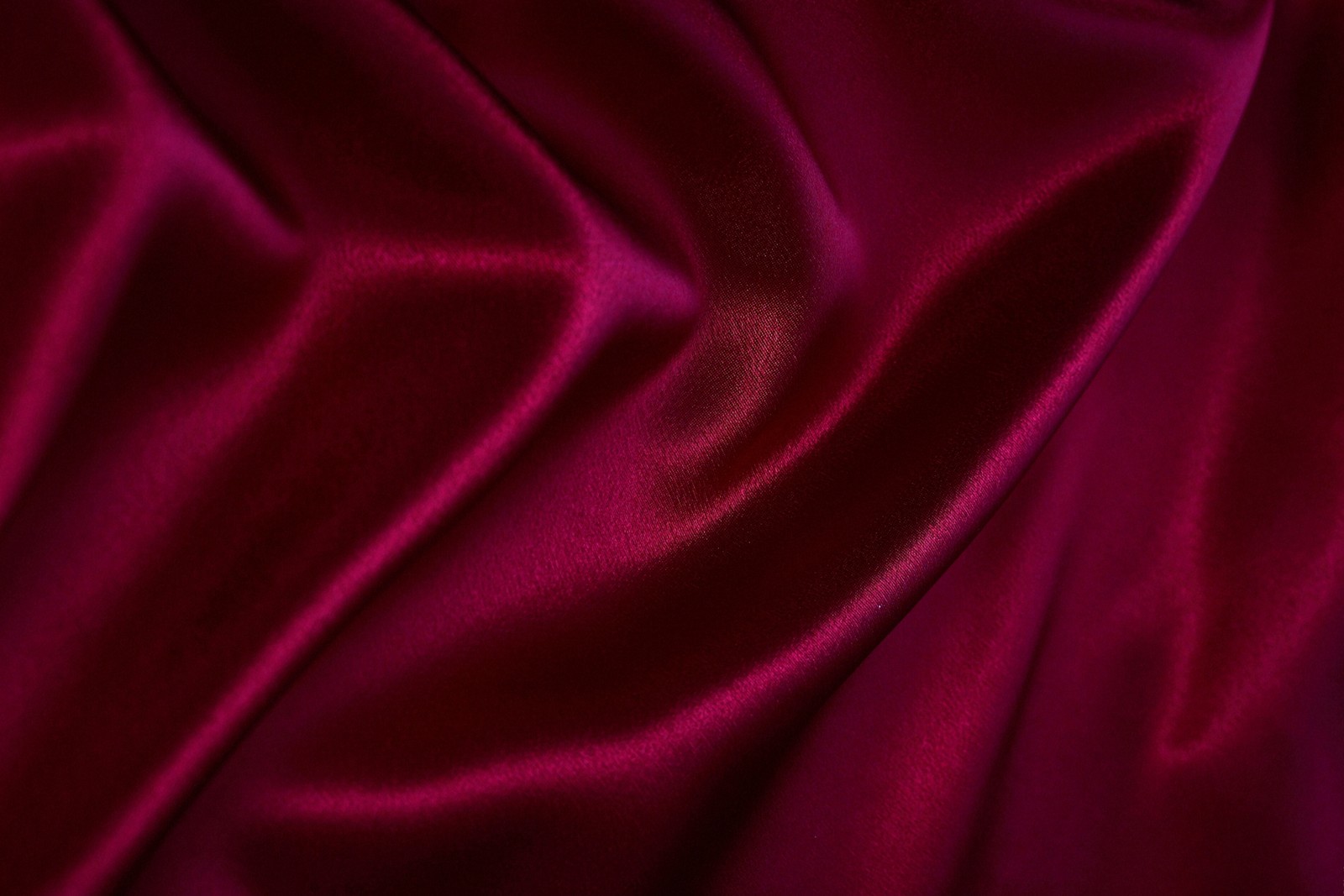 Un gros plan d'un tissu en satin rouge avec une très longue ligne (soie, textile, rouge, rose, violet)