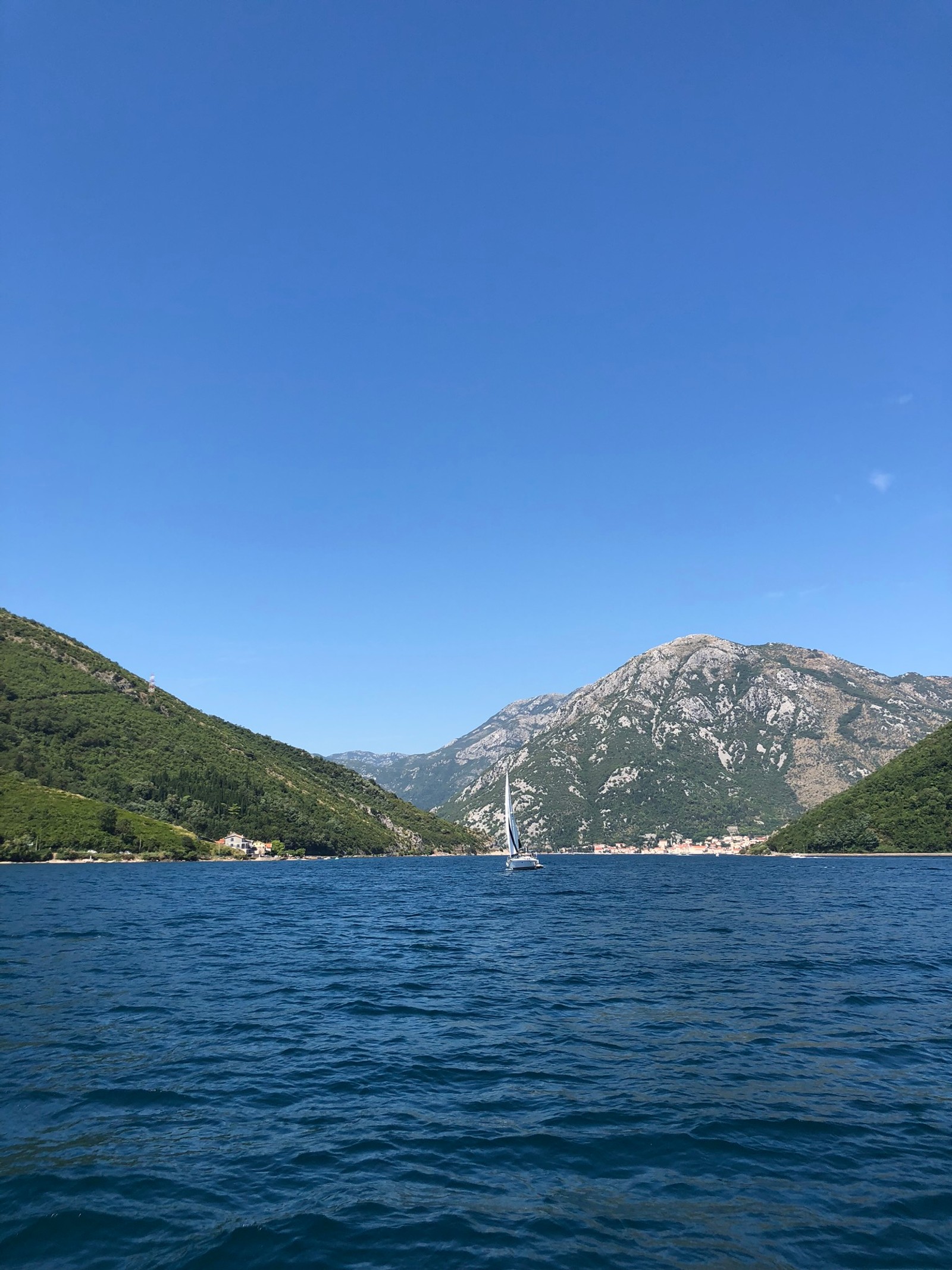 Arafed sailboat in the middle of a large body of water (mountainous landforms, water resources, highland, mountain range, hill)