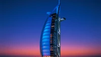 Burj Al Arab ao crepúsculo, exibindo sua silhueta icônica contra um céu colorido.