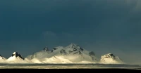 Schneebedeckte Bergkette unter dramatischen Wolken