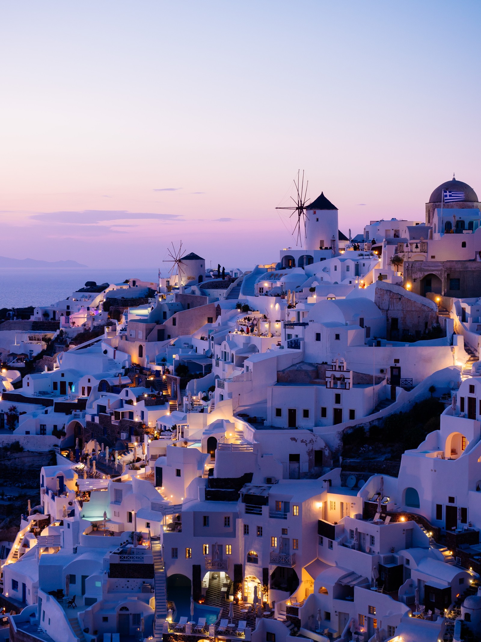 Vista arafed de uma cidade com um moinho de vento e uma piscina (santorini, viagem, cidade, assentamento humano, anoitecer)