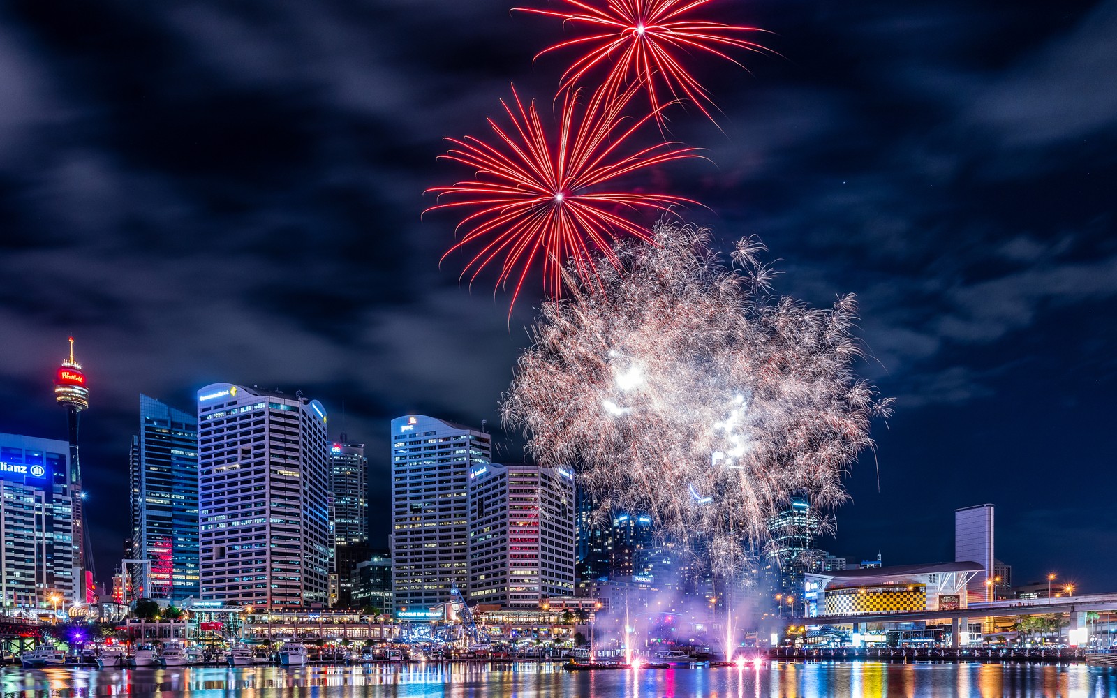 Des feux d'artifice dans le ciel au-dessus d'une ville avec une rivière et un bateau (feux dartifice, darling harbour, sydney, australie, ville nocturne)