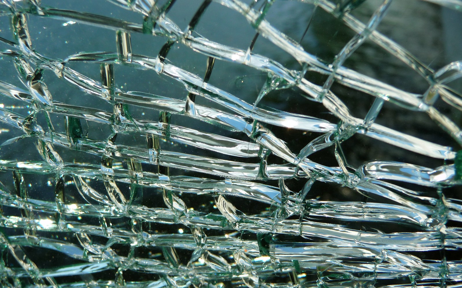 A close up of a broken glass window with a lot of glass (water, glass, wire fencing, metal, texture)