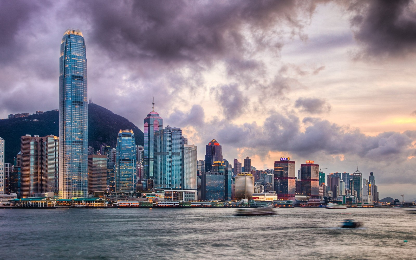 Une vue aérienne de la ligne d'horizon d'une ville avec un bateau dans l'eau (victoria harbour, victoria peak, paysage urbain, ville, horizon)