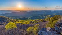 Nascer do sol sobre montanhas altas e encostas verdes exuberantes