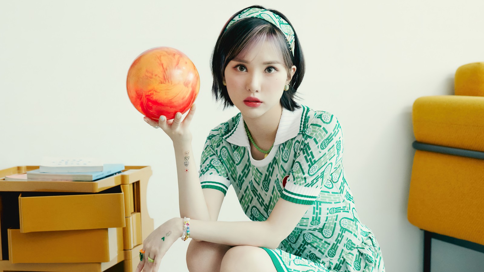 Une femme arabe en robe verte tenant une boule de bowling rouge (viviz, 비비지, k pop, filles, groupe de filles coréen)