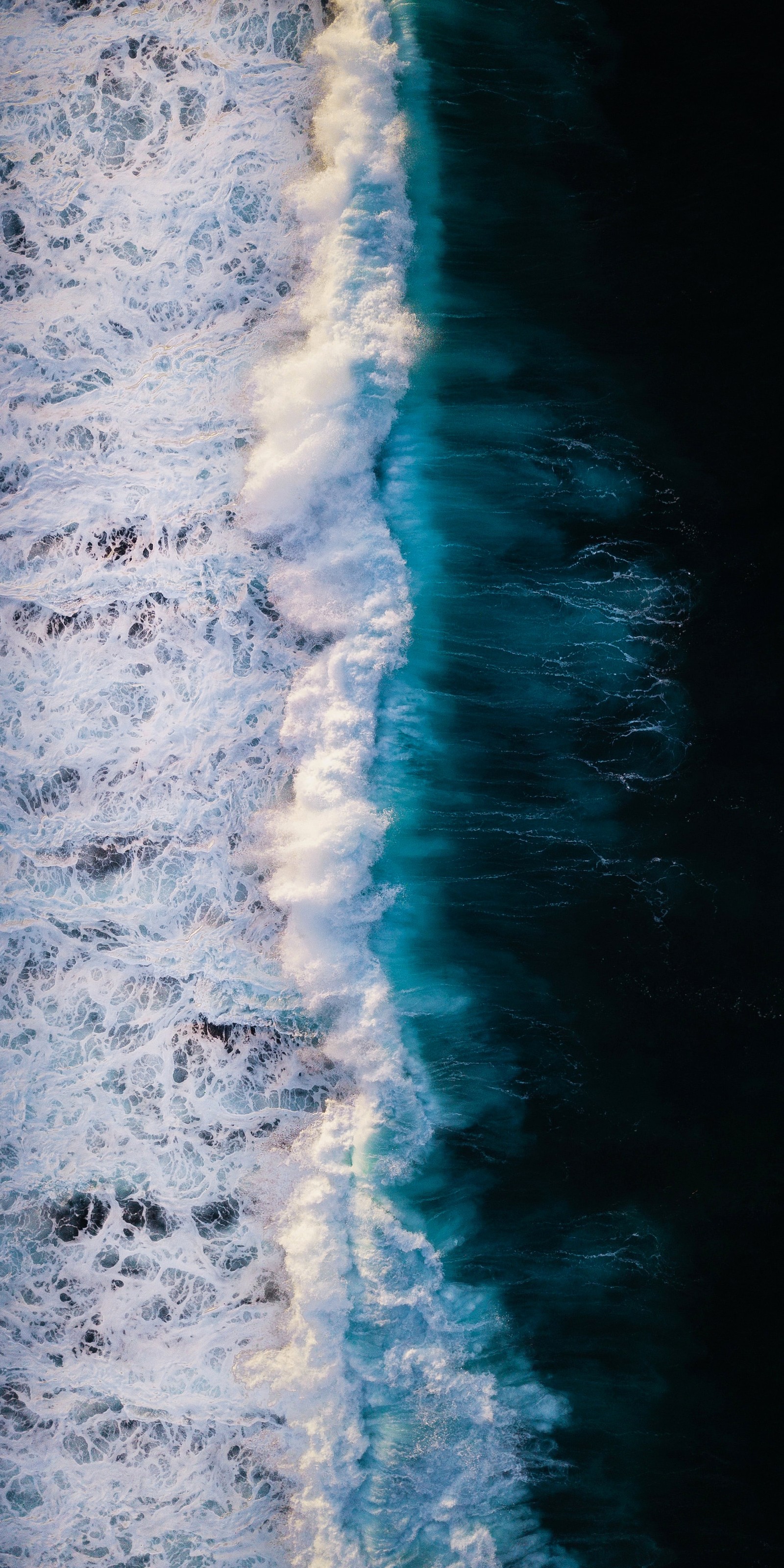 Araffe surfers are seen from above as they surf in the ocean (smartphone, ios, water, water resources, cloud)