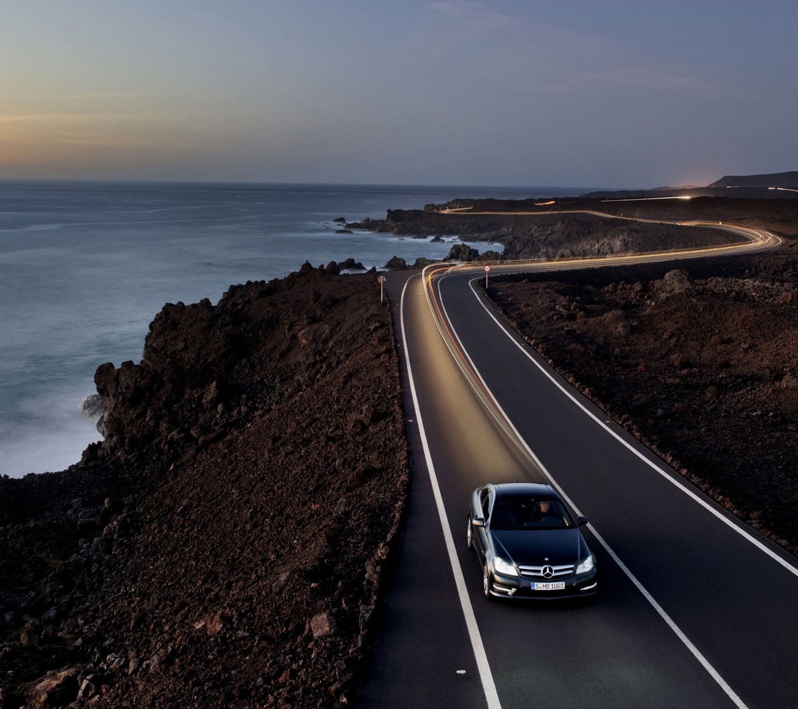 Vista aérea de um carro dirigindo em uma estrada perto do oceano (paisagem, mercedes, estrada, mar)