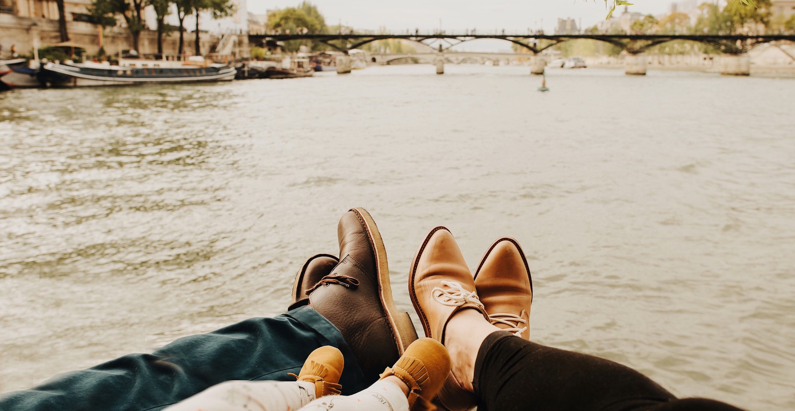 Deux personnes assises dans un bateau sur l'eau. (famille, bonheur, chaussures, jambe, loisir)