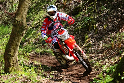 Piloto em ação em uma motocicleta de enduro através de uma trilha na floresta