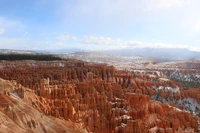 Snow-dusted red rock formations and towering hoodoos under a clear winter sky in Bryce Canyon National Park.