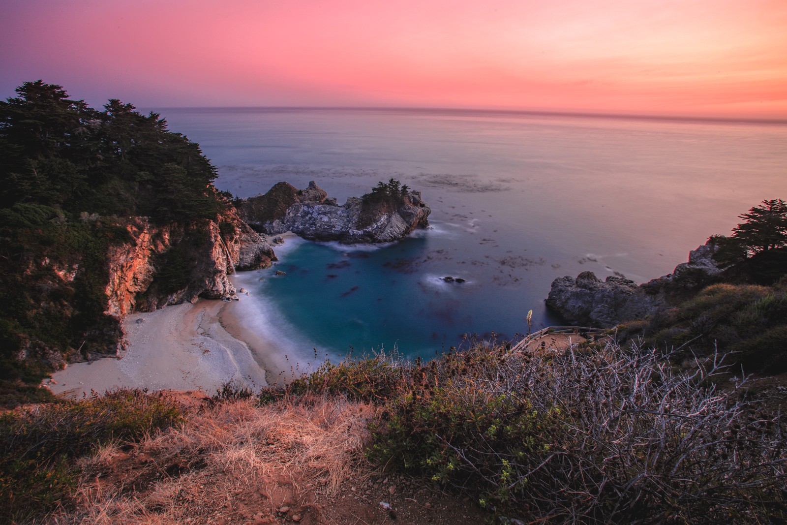 Une vue d'une plage avec de l'eau et des arbres (plage, paysage, horizon, coucher de soleil, heure dorée)