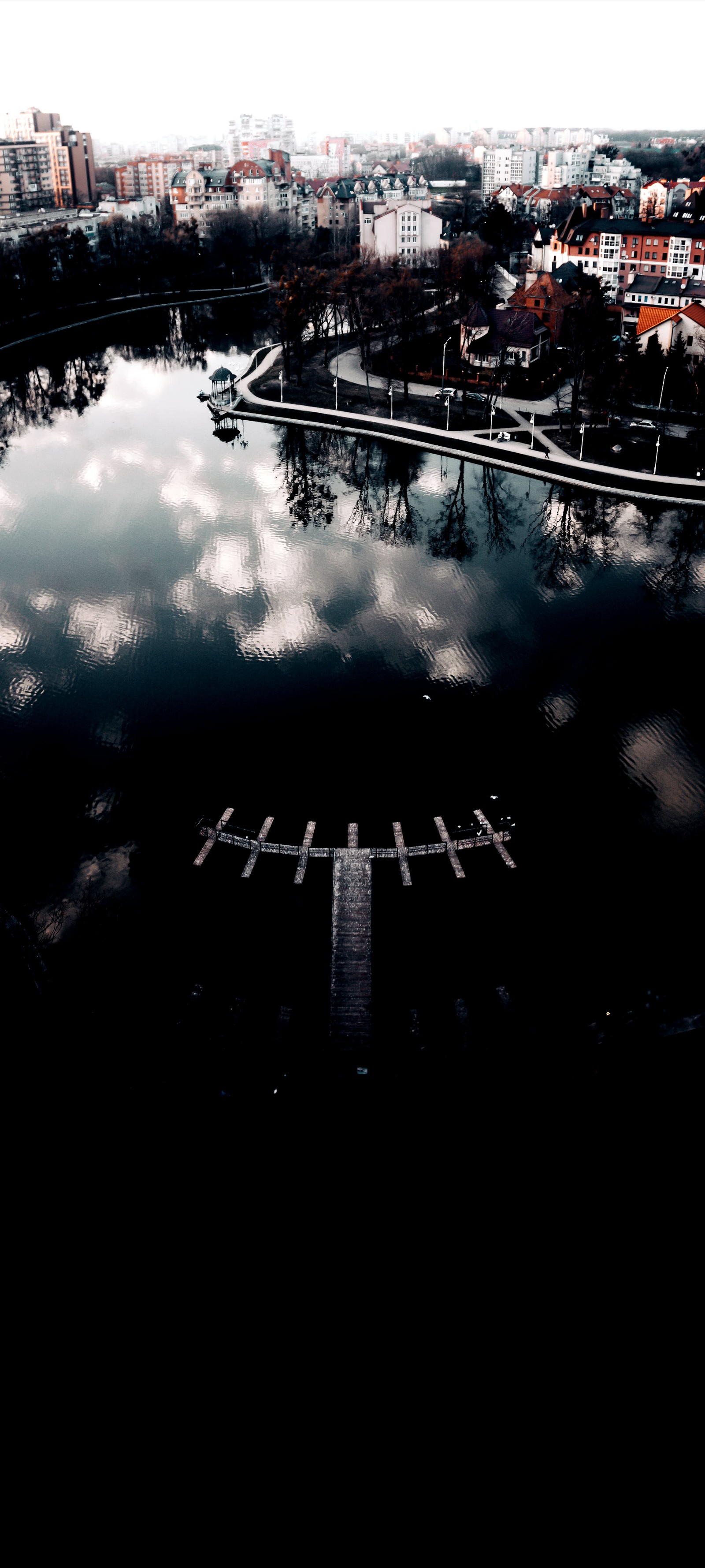 There is a picture of a lake with a dock in it (reflection, water, cloud, automotive tire, asphalt)