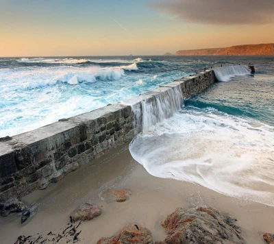 Serenidad costera: Las olas abrazan el muelle de piedra al atardecer