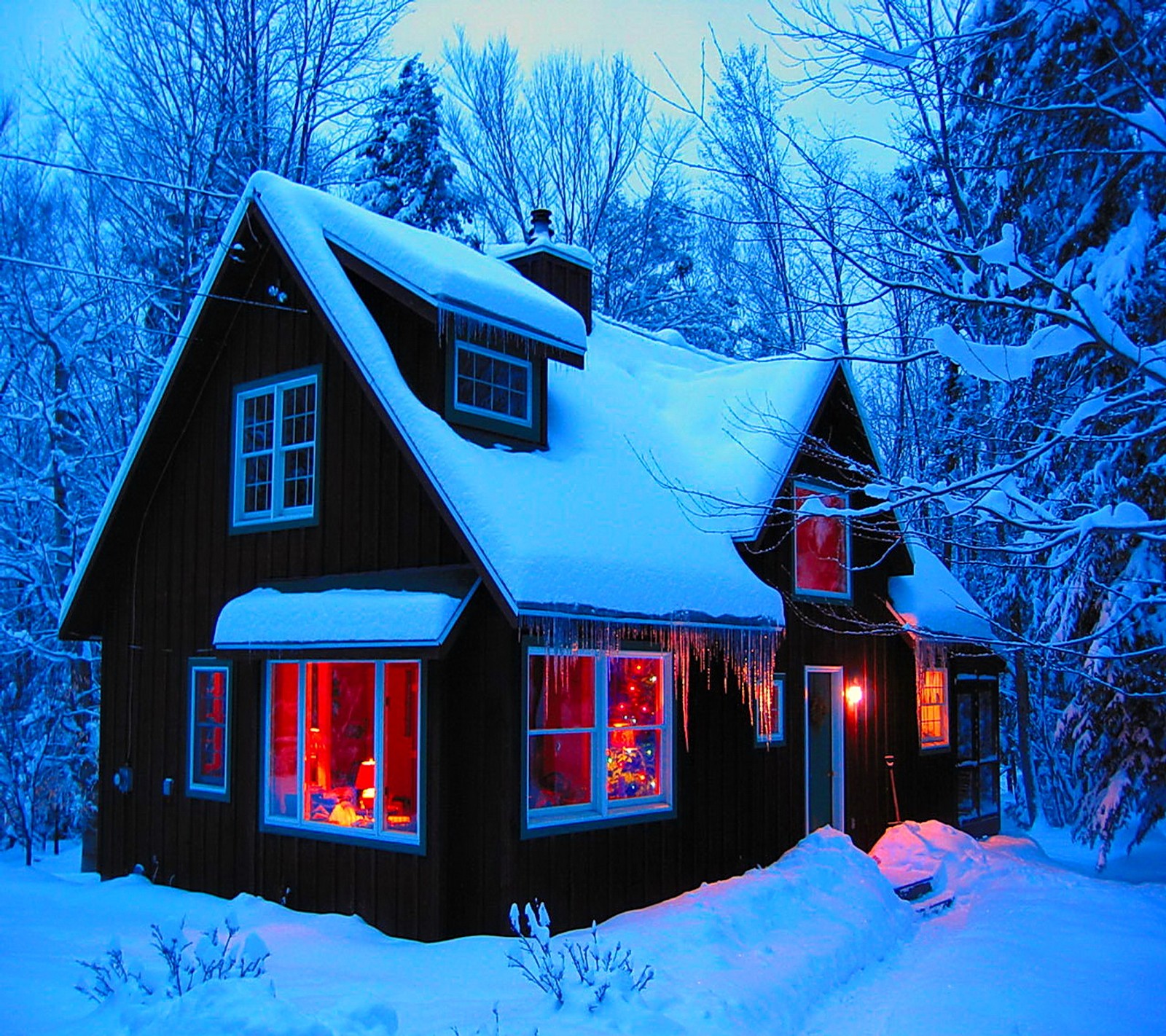 Arafed house with a lit window and a christmas tree in the front (house, snow, winter)