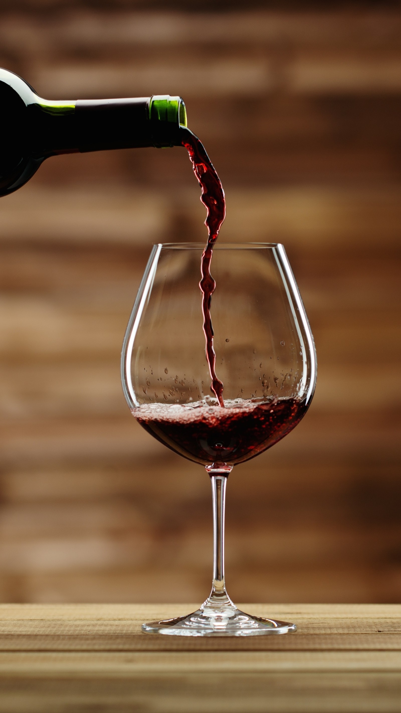 Araffe pouring red wine into a glass on a wooden table (art, beauty, bottle, glass, wine)