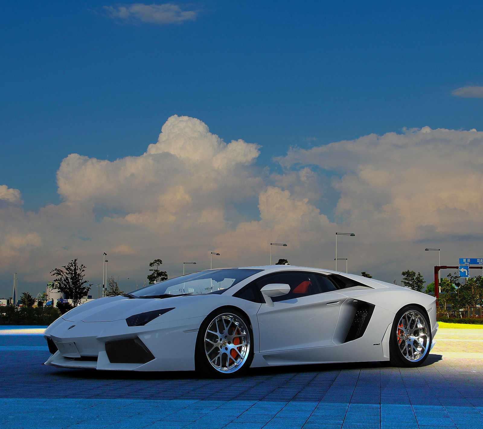 Um carro esportivo branco estacionado em um estacionamento com um céu nublado (carro, carros, lamborghini)