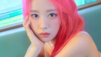 Yves do LOONA com cabelo rosa marcante, olhando pensativamente.