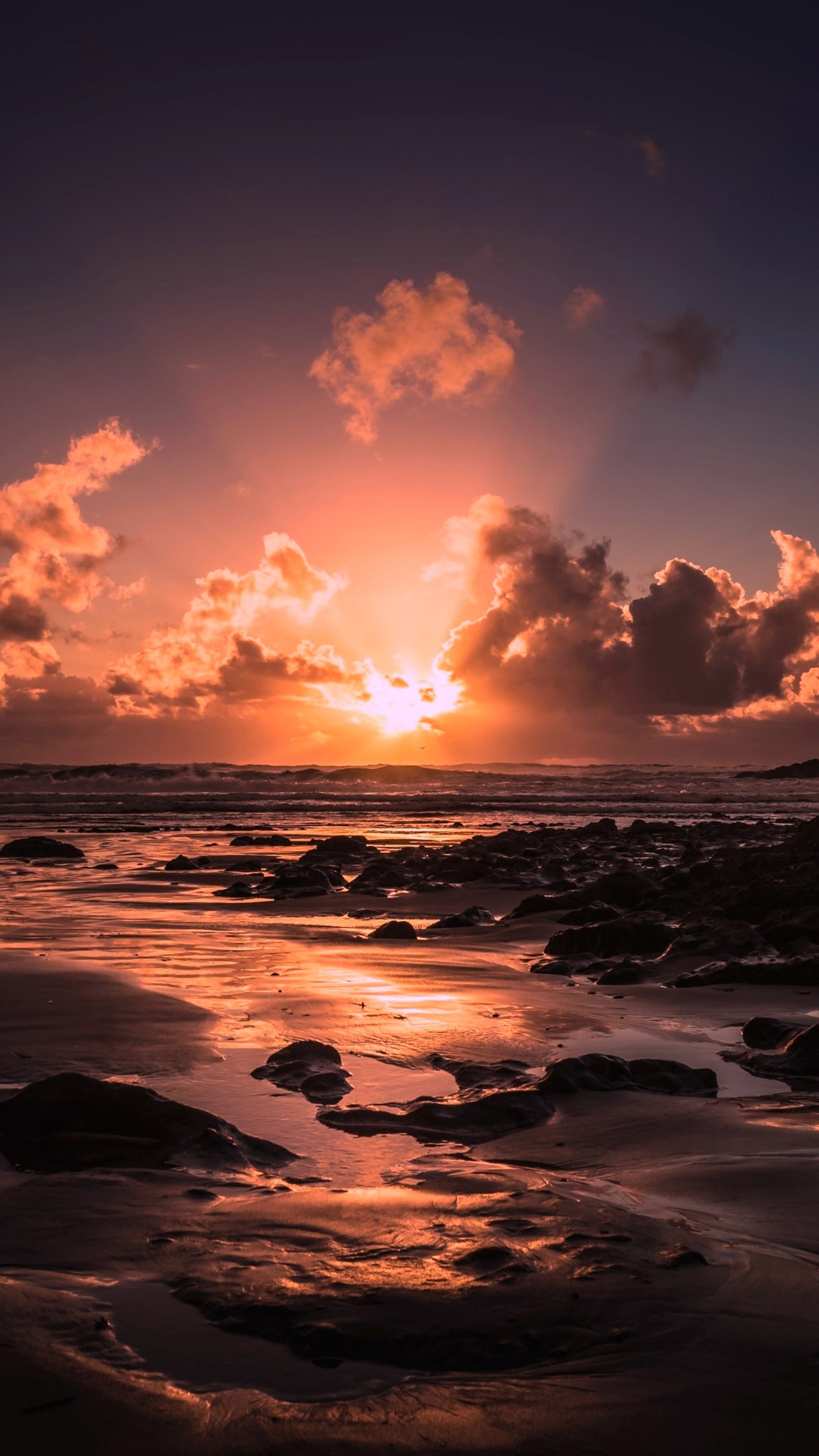 Vue d'un coucher de soleil sur l'océan avec des rochers et du sable (eau, nuage, ressources en eau, atmosphère, crépuscule)