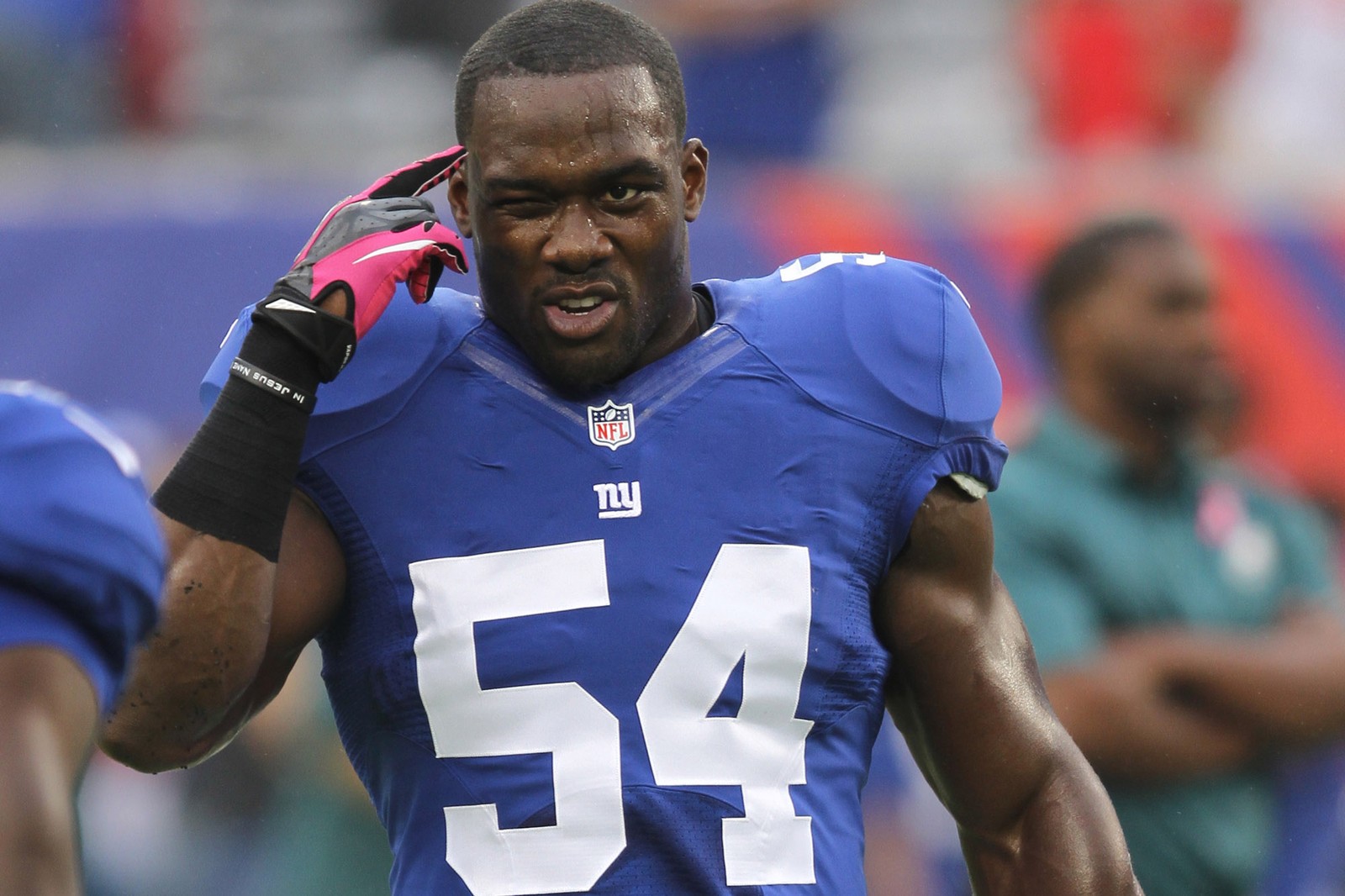 A close up of a football player holding a glove on his head (american football, new york giants, nfl, football player, player)