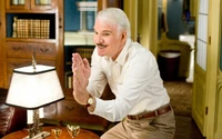 Steve Martin gesticula de forma brincalhona em uma sala aconchegante e bem iluminada, incorporando humor e charme nesta imagem do filme.