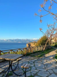 Paisagem serena à beira do lago com montanhas e caminho de madeira