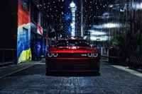 Dodge Challenger SRT Hellcat dans une ruelle urbaine vibrante illuminée par des guirlandes lumineuses.