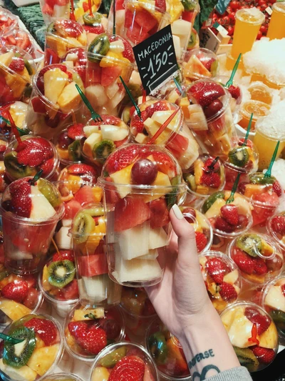 Tazas de frutas coloridas desbordantes de fresas, kiwi y melón, perfectas para un aperitivo o postre refrescante en un brunch.