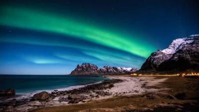 Faszinierende Aurora Borealis über den schneebedeckten Bergen und der felsigen Küste der Lofoteninseln