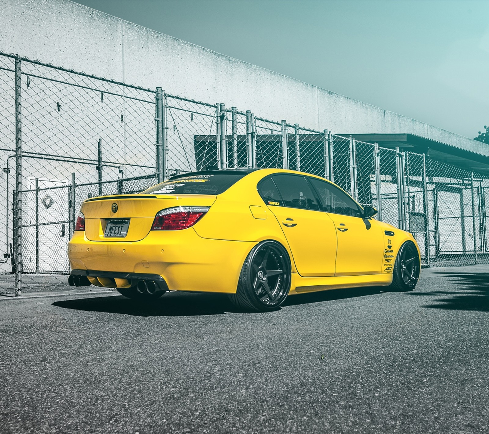 Arafed yellow car parked in front of a fenced in building (bmw, e60, m5, sedan, tuning)