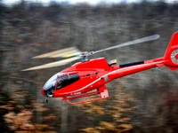 Eurocopter EC130 rouge en vol : Une vitrine dynamique de l'excellence aéronautique