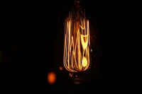 Illuminated Amber Vintage Light Bulb in Darkness