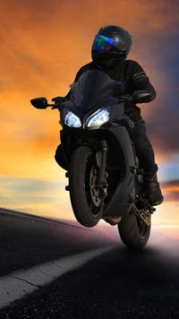 Motorcycle Rider Performing a Wheelie Against a Sunset Background